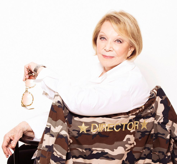 A photo for former Allure plastic surgery reporter Joan Kron sitting in a director's chair holding her glasses